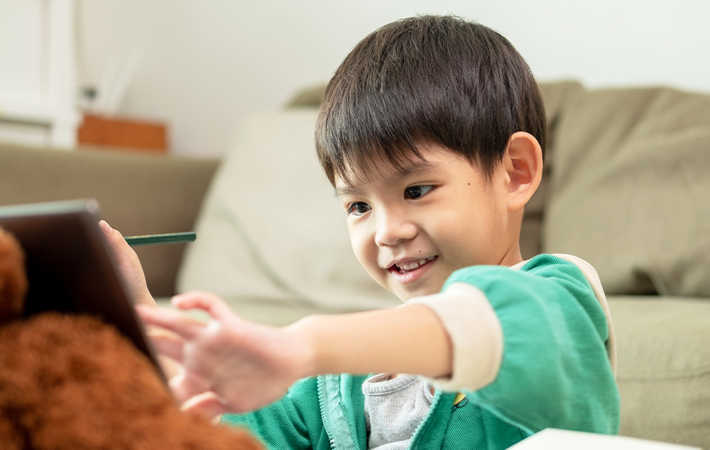 タブレットを使って学習する男の子と女の子、それを見守る大人の女性