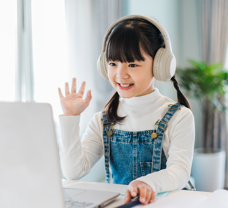 ヘッドフォンをつけて手を振りながらパソコンで英会話する女の子