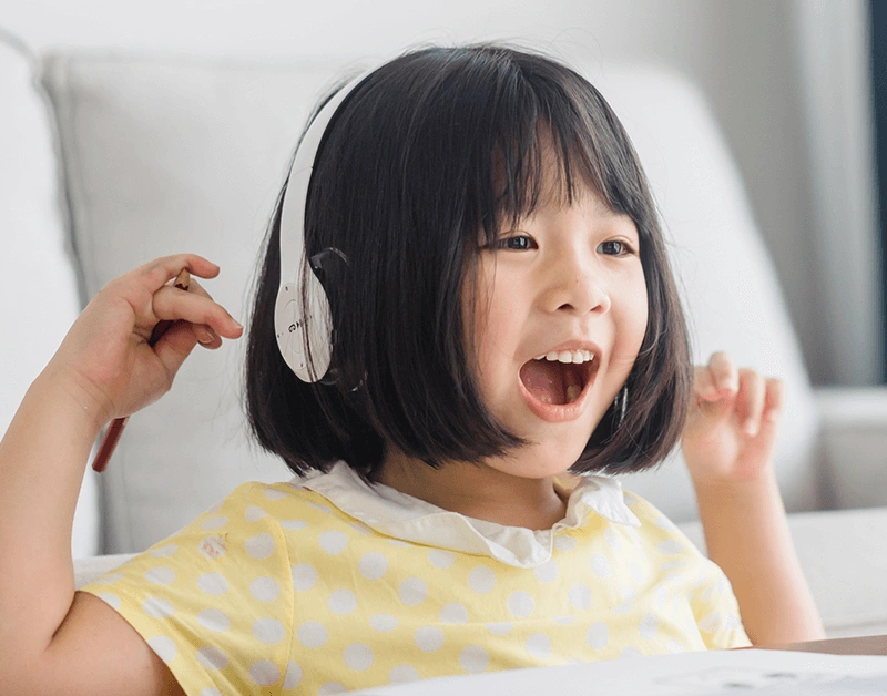 自宅のリビングで、キャラクター先生とオンライン英会話レッスンを楽しむ女の子
