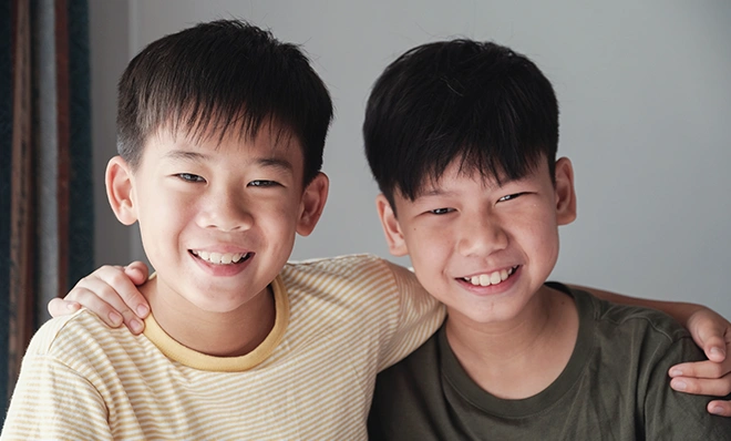 肩を組んで仲良く笑顔を見せる、小学生の男の子の兄弟