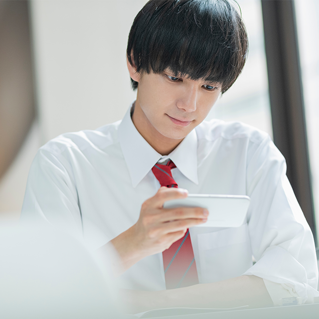 スマートフォンを見ながら学習している男子学生
