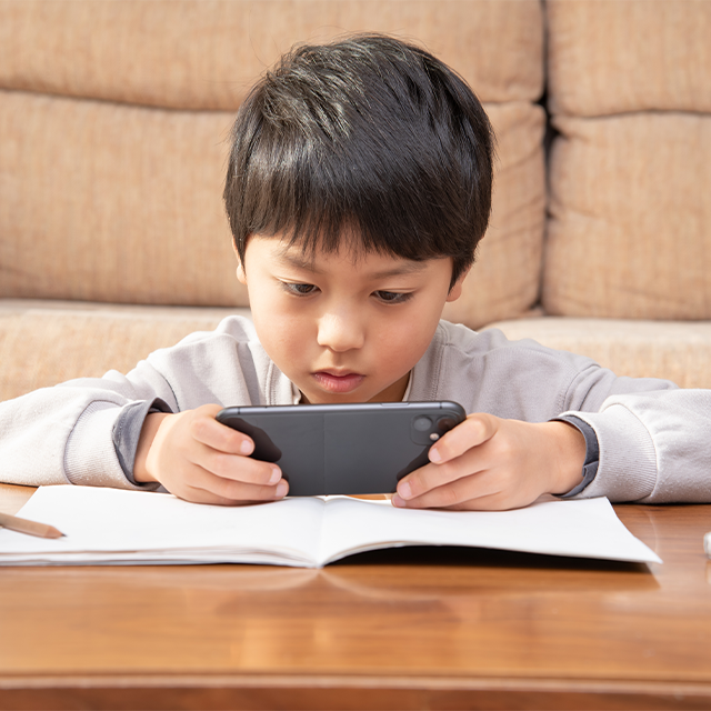 スマートフォンを見ながら勉強する小学生の男の子