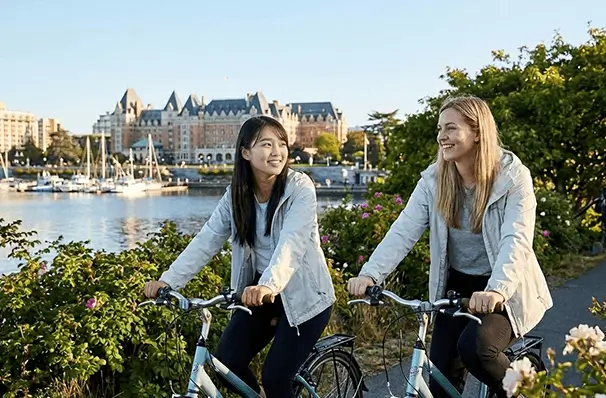 ビクトリアの海沿いをサイクリングする女性観光客