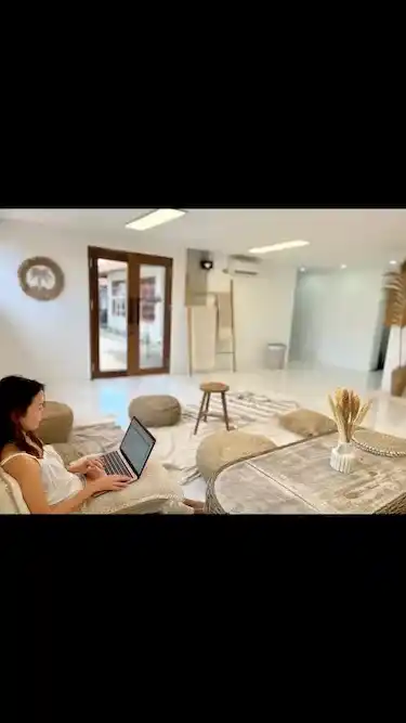 明るい屋内ラウンジでパソコンを使用する人物、現代的なインテリア