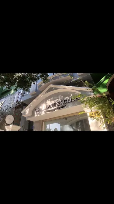 Brilliant Englishの看板がある語学学校の屋外入口、緑の植物