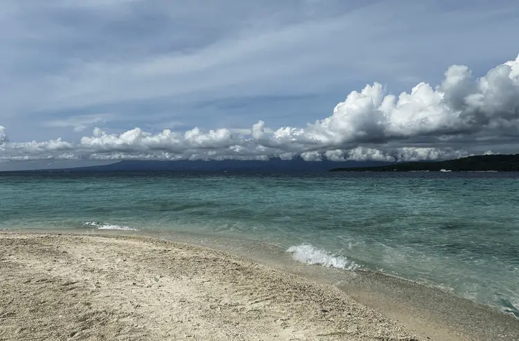 波打ち際と雄大な雲が広がるビーチの景色